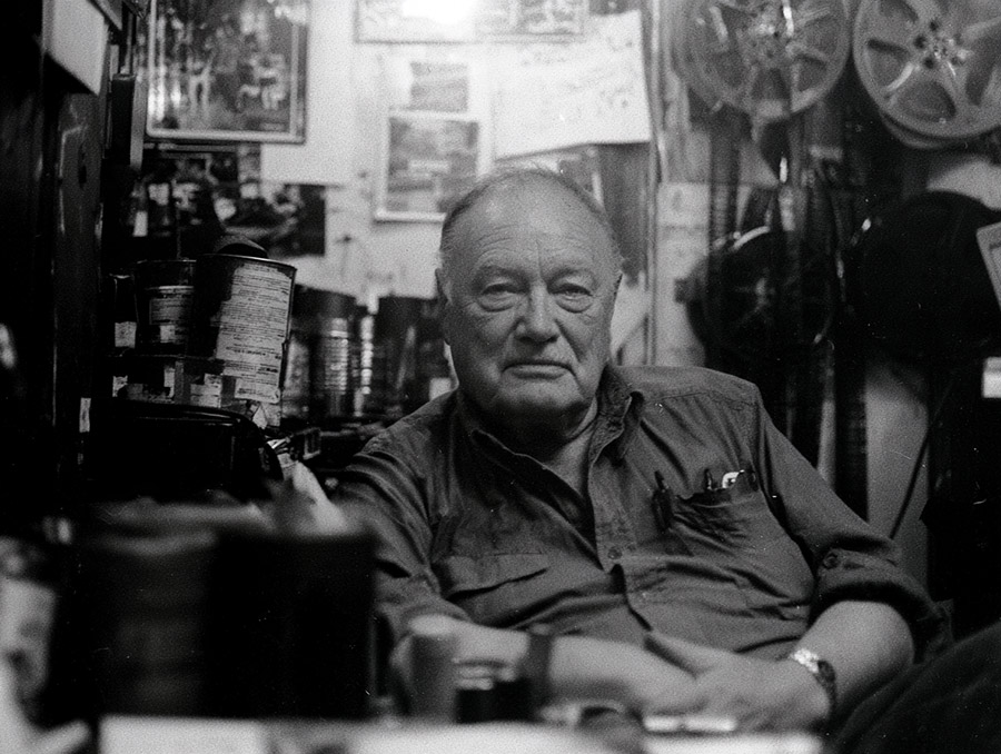 Miles H. Sheridan, seated among his collection of film reels and canisters